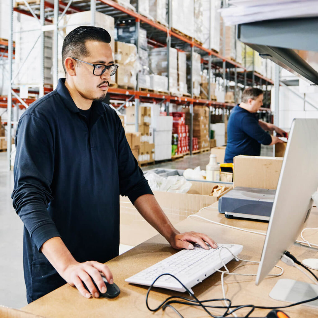 Man working at a computer in a warehouse.