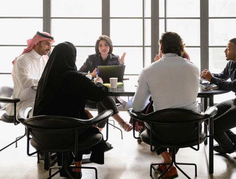 Co-workers sitting at a table having a meeting and discussing the digital future.